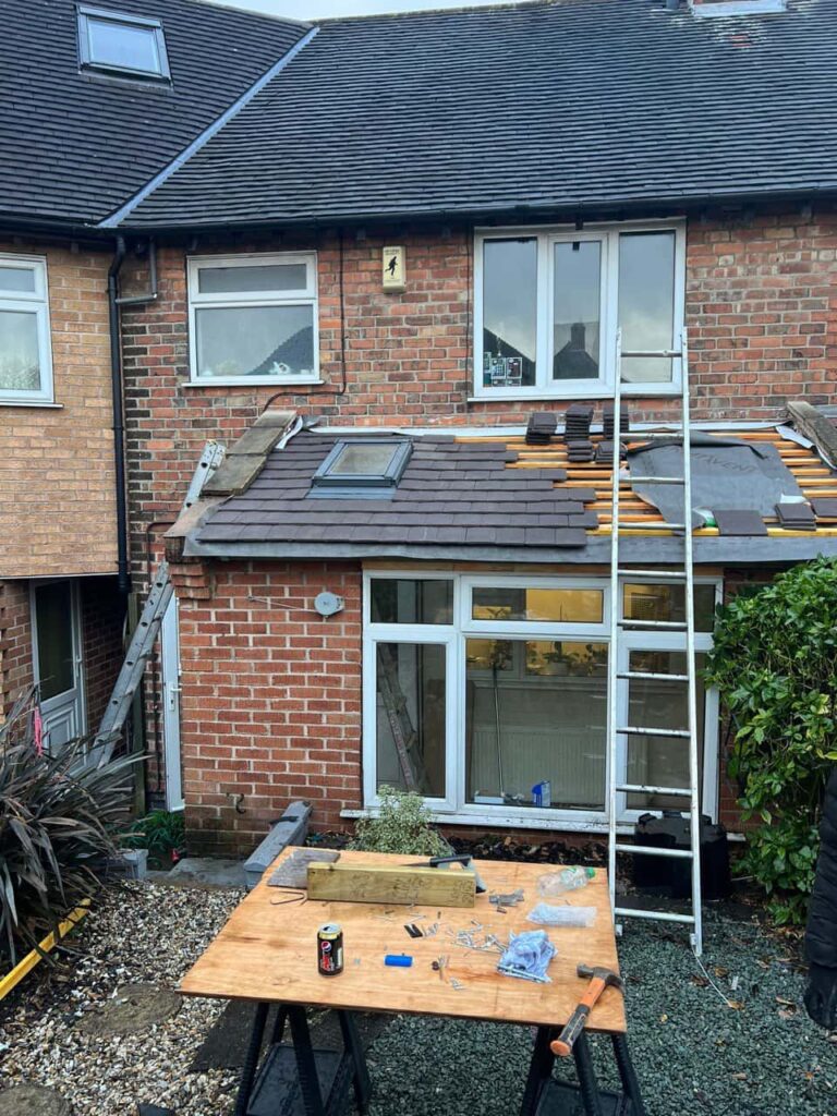 This is a photo of a roof extension that is having new roof tiles installed. This is a photo taken from the roof ridge looking down a tiled pitched roof on to a flat roof. Works carried out by Hassocks Roofing Repairs