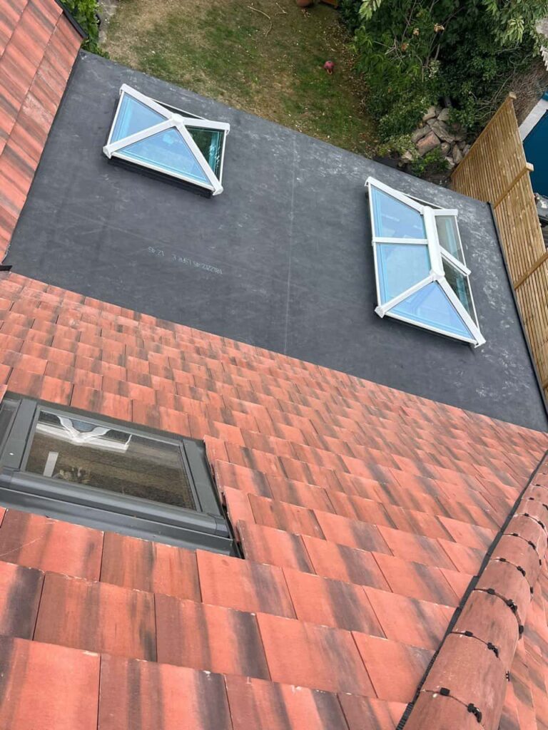This is a photo taken from the roof ridge looking down a tiled pitched roof on to a flat roof. Works carried out by Hassocks Roofing Repairs